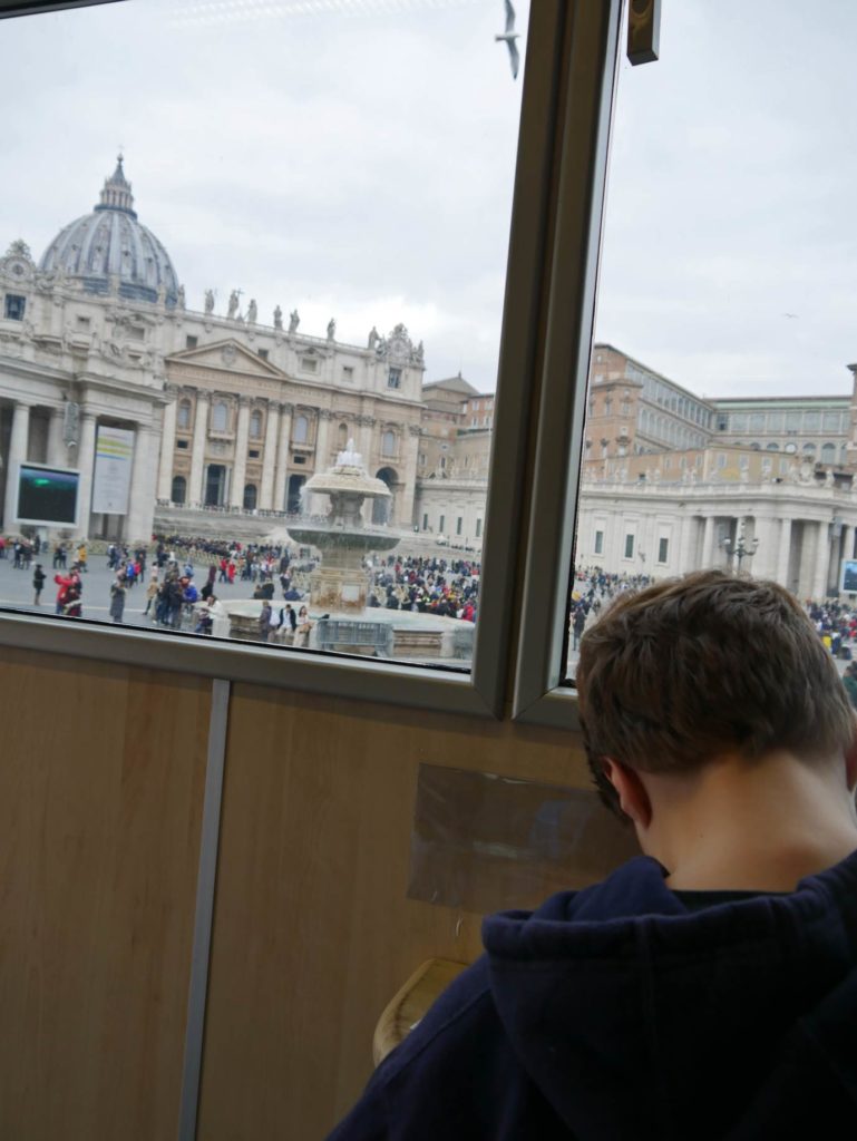 kind-schreibt-postkarte-in-vatikanischer-post-mit-blick-auf-petersdom