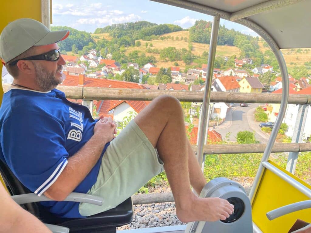 mann-faehrt-in-solar-draisine-im-odenwald-mit-blick-auf-dorf