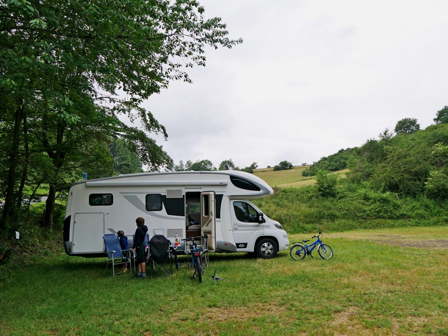 familie-vor-wohnmobil-auf-gruener-wiese