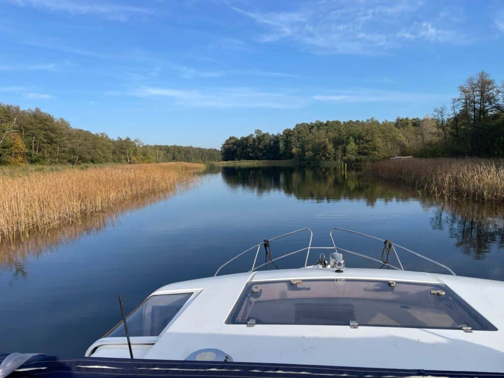 hausboot-fährt-über-havel-vorbei-an-schilf